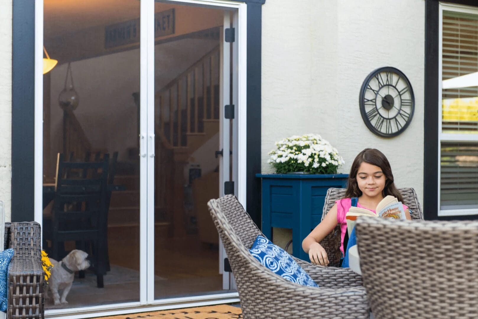 A girl sitting in a chair outside of a sliding glass door.