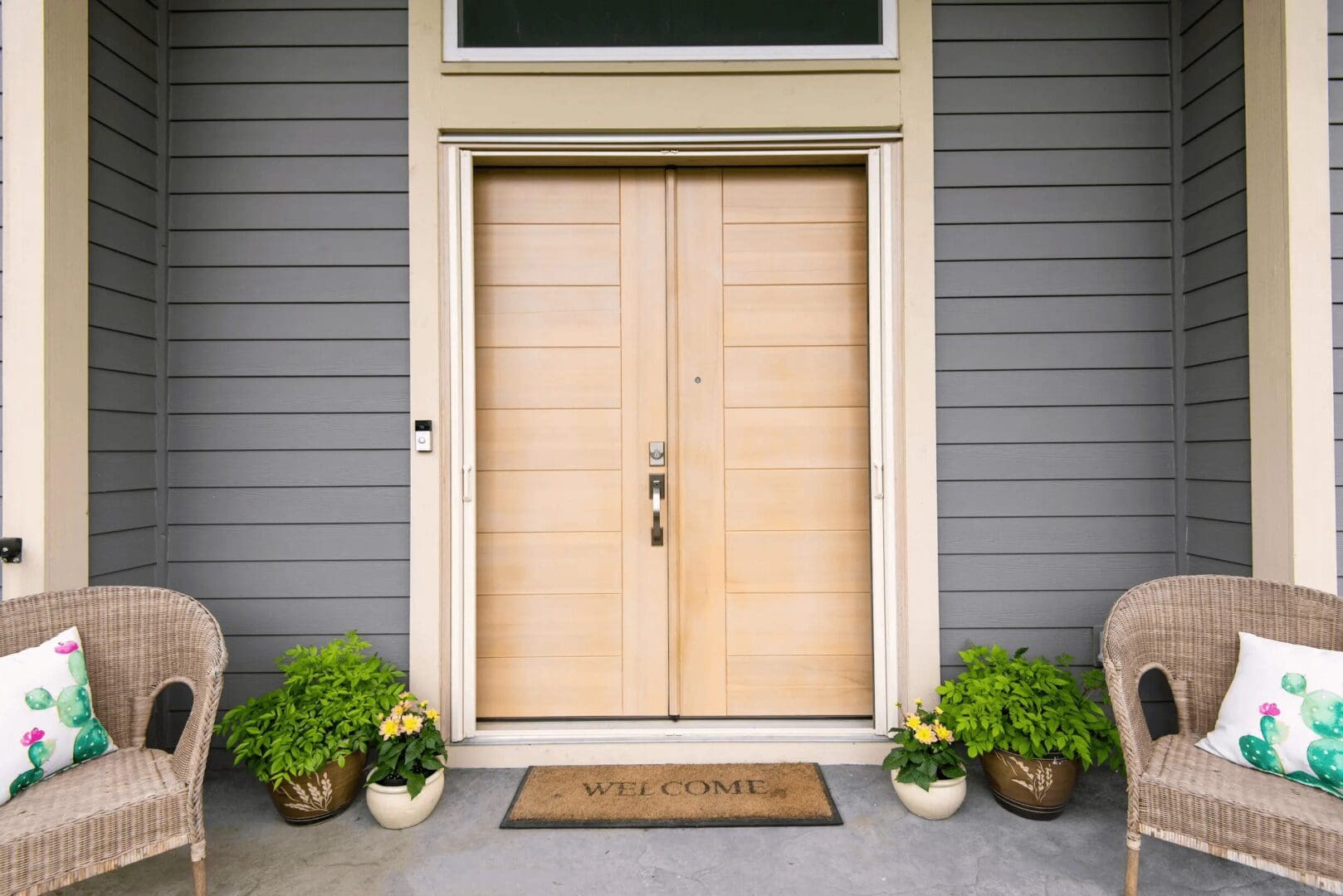 A front door with two wooden doors and plants.