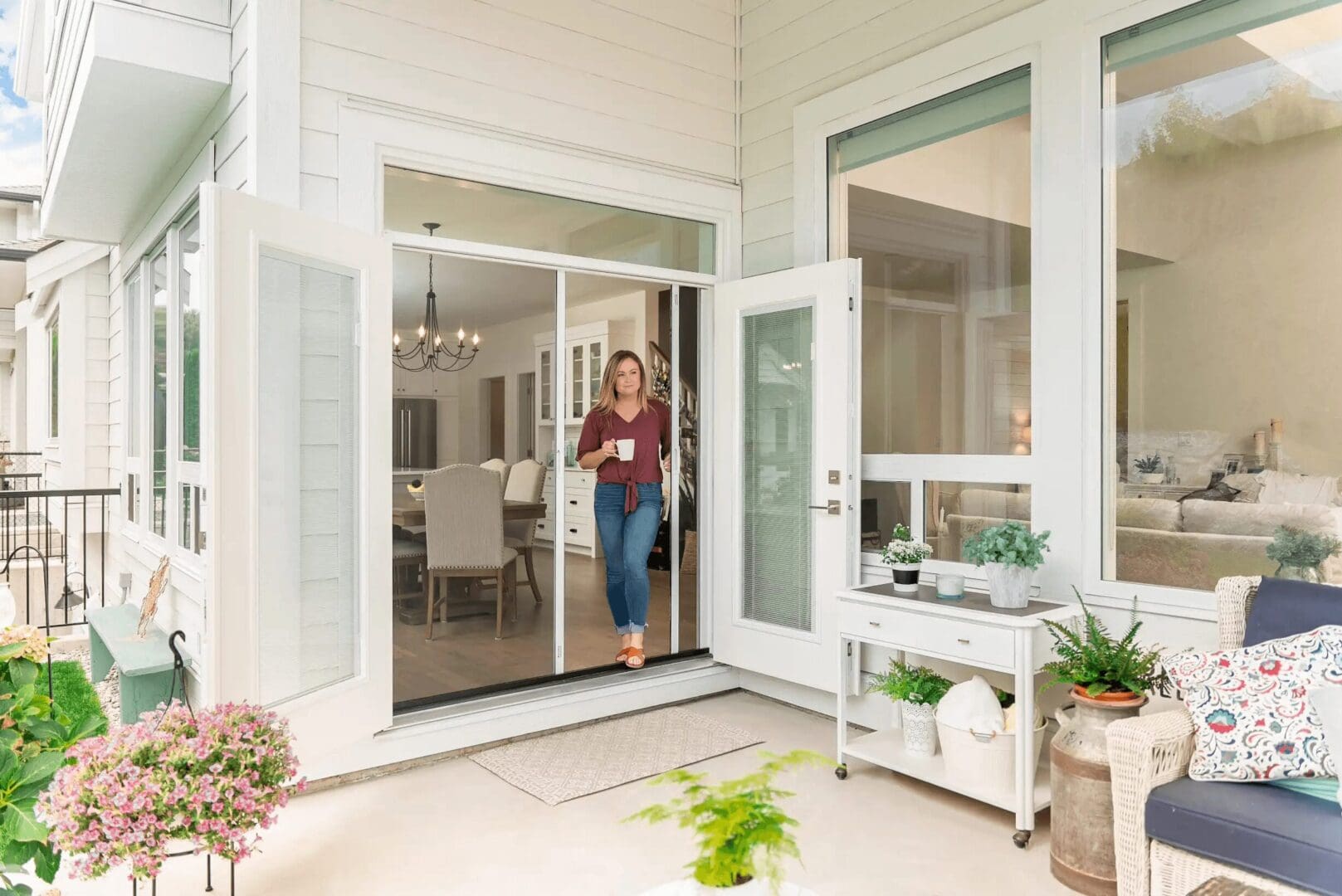 A woman standing in front of an open sliding glass door.