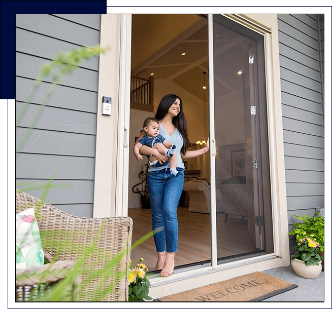 A woman holding her baby in front of a screen door.