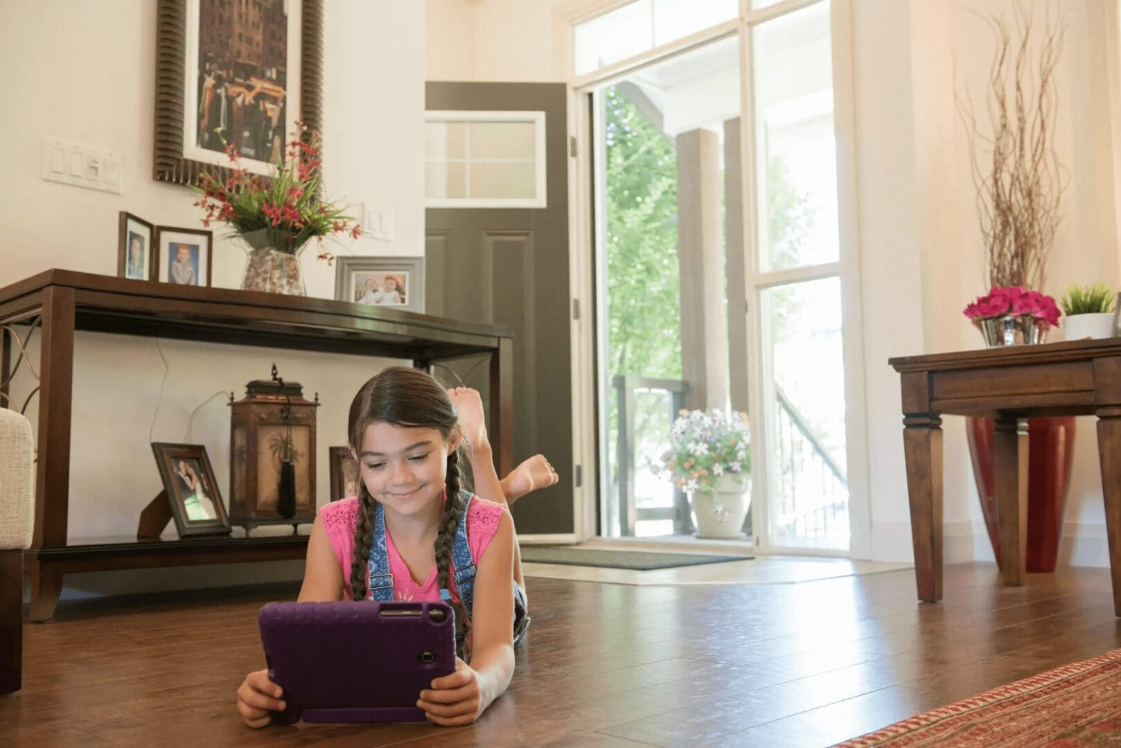 A girl is laying on the floor using her tablet.