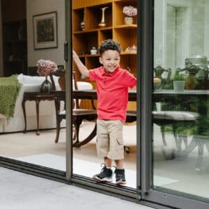 A boy standing in front of a sliding glass door.