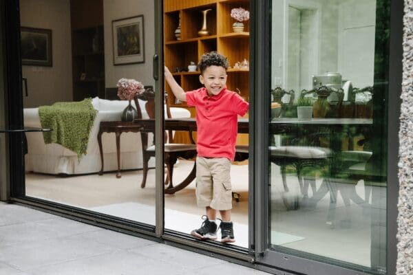 A boy standing in front of a sliding glass door.