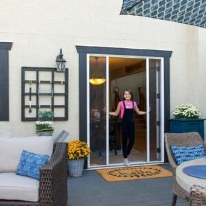 A woman standing in front of an open screen door.