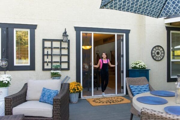 A woman standing in front of an open screen door.