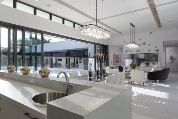 A kitchen with white counters and large windows.